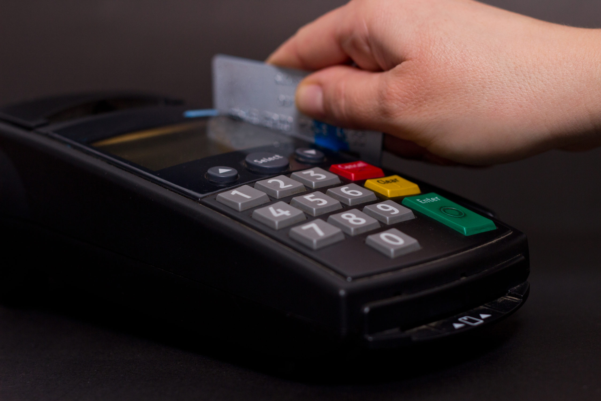 Hand Swiping Credit Card In Store. Female hands with credit card and bank terminal. Color image of a POS and credit cards Hand Swiping Credit Card In Store. Female hands with credit card and bank terminal. Color image of a POS and credit cards.